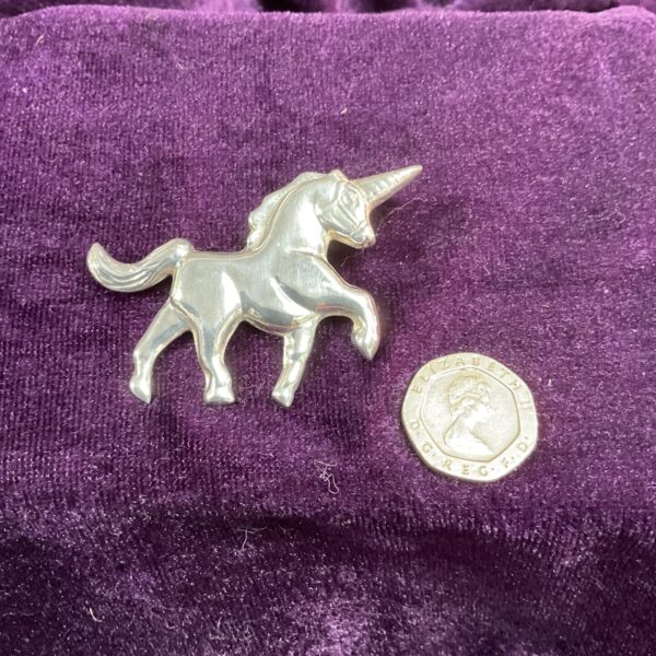 Close-up of a detailed silver unicorn brooch.