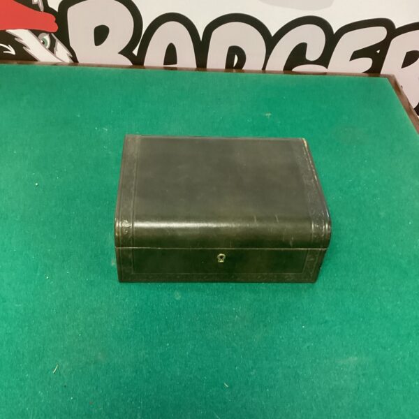 Dark brown leather jewellery box on green surface.