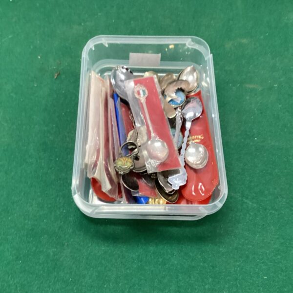 Lot of vintage and collectable teaspoons in a display case.