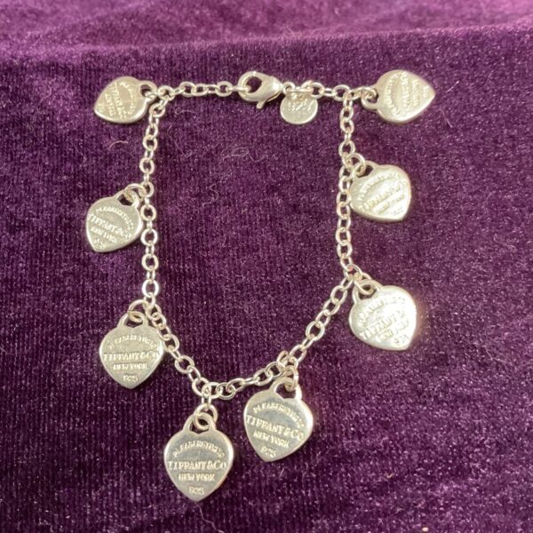 Vintage Tiffany silver heart charm bracelet with multiple charms.