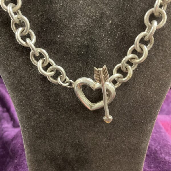 Silver chain necklace with heart and arrow pendant.