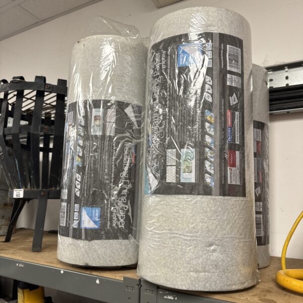Four rolls of graphite insulating lining paper stacked on a shelf.
