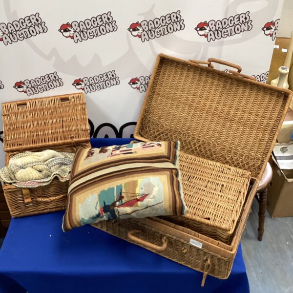 Three vintage wicker picnic baskets with a patterned rug.