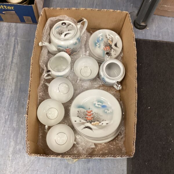 Vintage Japanese tea set with landscape design on a table.