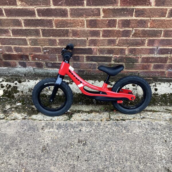 Red Vitus balance bike for kids learning to cycle.