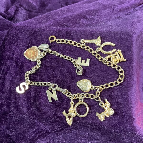 Vintage yellow metal charm bracelet with twelve charms.