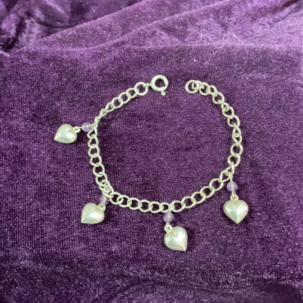 Delicate 925 silver heart charm bracelet on a purple background.