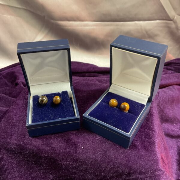 Close-up of two pairs of silver tiger eye stud earrings.