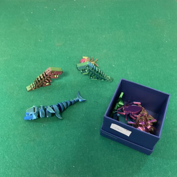 Colourful 3D printed fidget toys on a green surface.