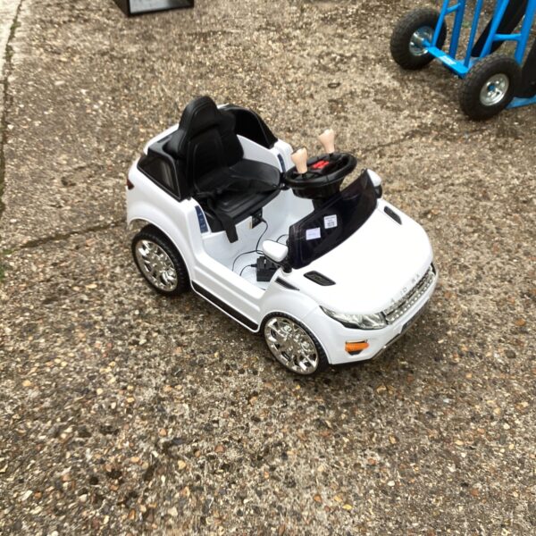 Side view of a white electric ride-on car for children.