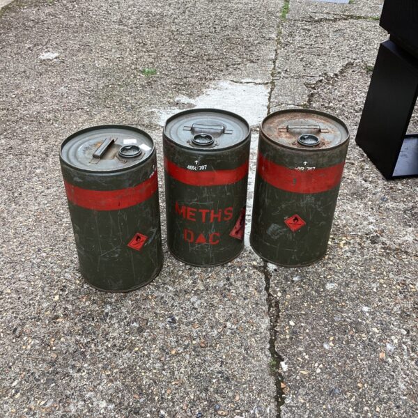 Three weathered steel oil drums for vintage industrial storage.
