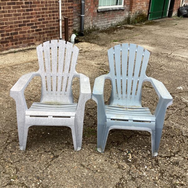 Pair of weathered plastic garden chairs for outdoor use.