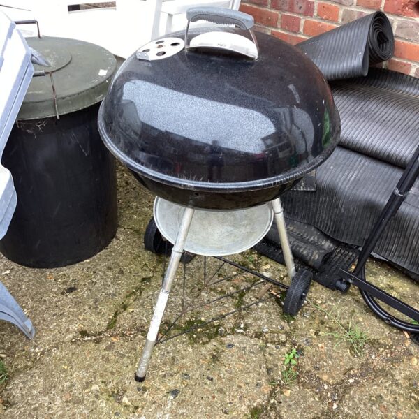 Vintage Weber BBQ grill in a garden setting.