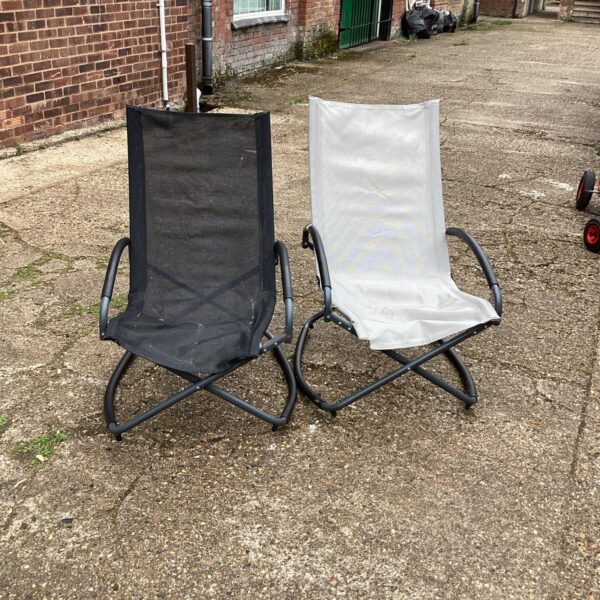 Pair of vintage garden chairs needing repair in a garden setting.