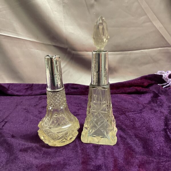 Two antique cut glass bottles with silver mounts, showing damage.