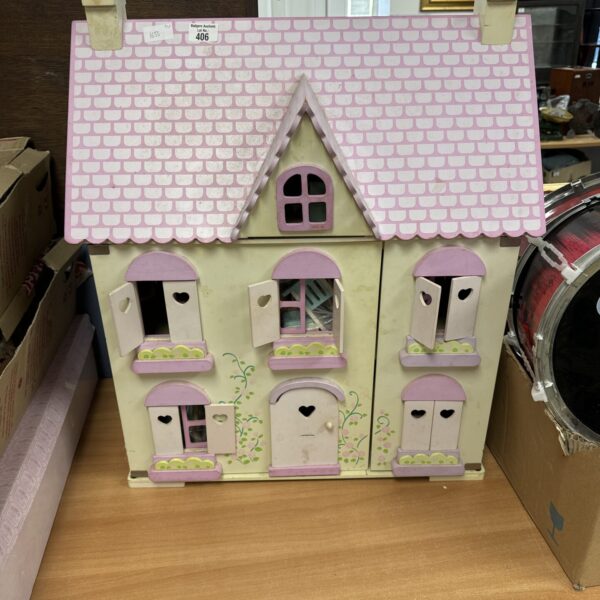 Pink vintage dolls house with detailed facade.