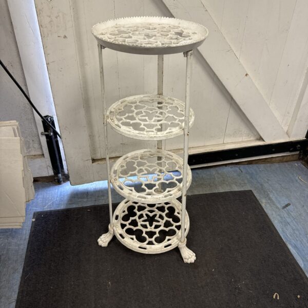 Vintage wrought iron plant stand with four tiers for displaying plants.