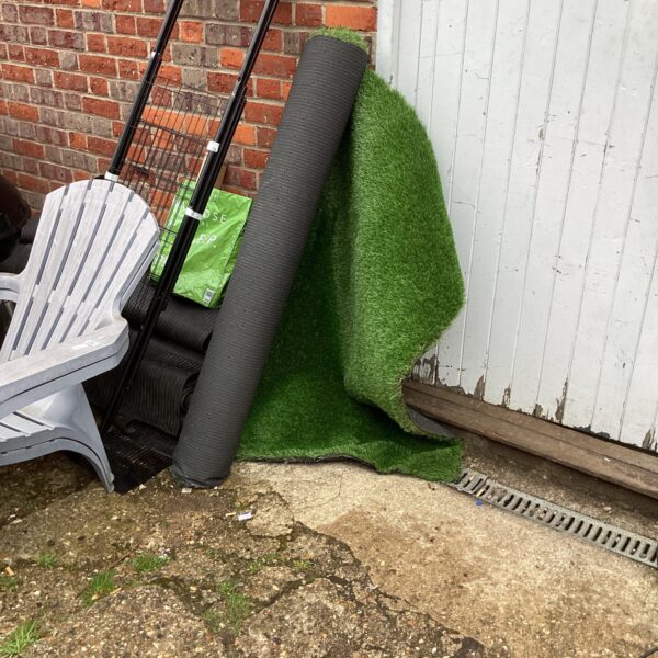 Roll of artificial grass in a garden setting.