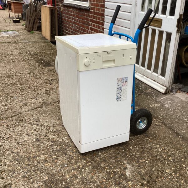 White Whirlpool slimline dishwasher on a trolley in a yard.