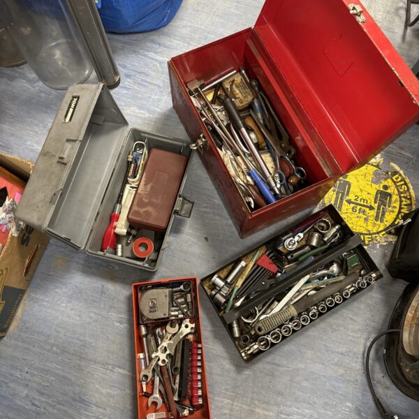 Red vintage toolbox filled with mechanic's tools and workshop equipment.
