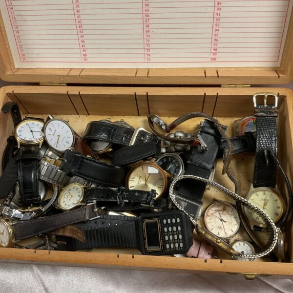 Wooden box filled with assorted vintage and repair wristwatches.