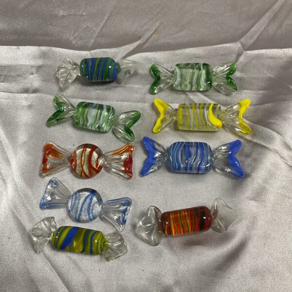 Lot of nine colourful Murano glass sweets on a white surface.