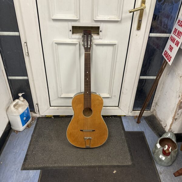Vintage acoustic guitar leaning against a white door.