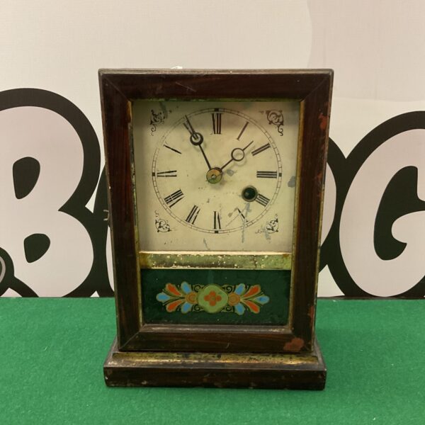 Antique American mantle clock with glass front and detailed face.