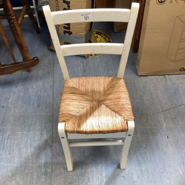 Vintage child's chair with woven seat and rustic charm.