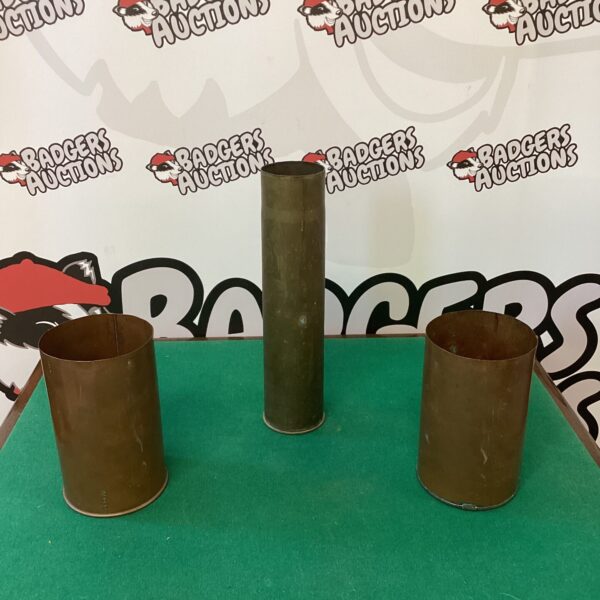 Vintage brass cannon shell and copper pots on display.