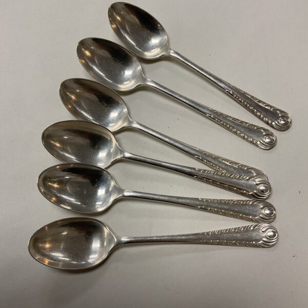 Set of six hallmarked sterling silver teaspoons on a white surface.