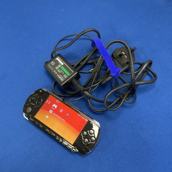 Sony PSP-3000 handheld console with charger, retro gaming device.