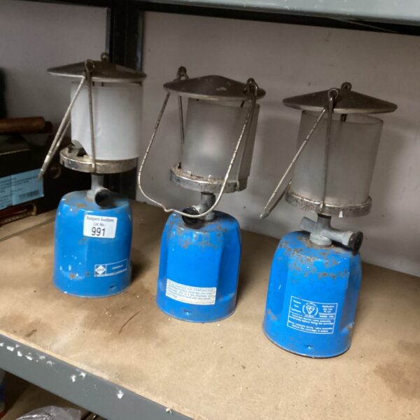 Three vintage gas camping lamps for outdoor use.