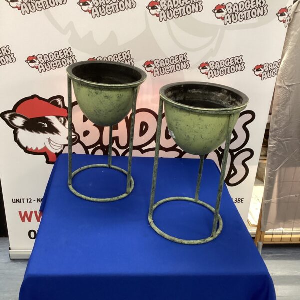 Two weathered metal plant stands for garden display.