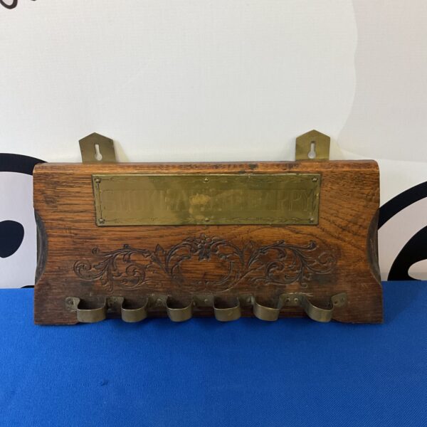 Vintage wooden pipe rack for displaying smoking pipes.