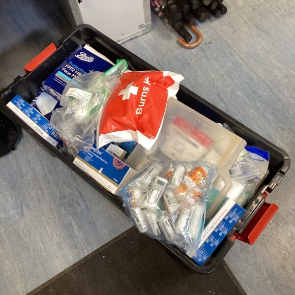 First aid kit with face masks and Covid tests inside a tub.