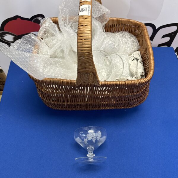 Vintage wicker basket filled with assorted glassware for display.