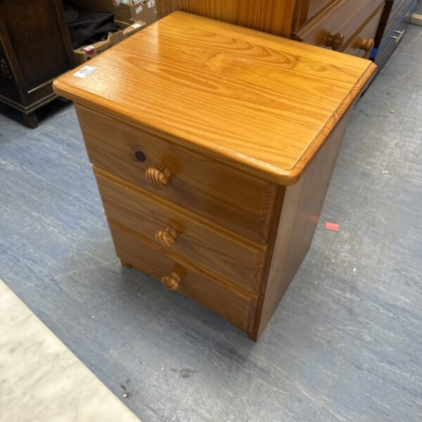 Vintage pine bedside cabinet with three drawers.