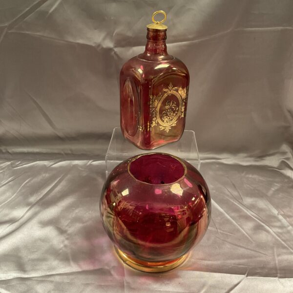 Vintage cranberry glass decanter and vase with gilt decoration.