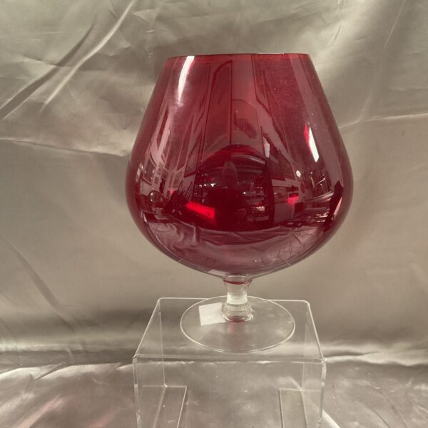 Large ruby red brandy glass balloon vase for display.