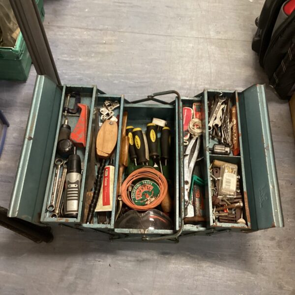 Vintage metal tool box filled with various tools and hardware.