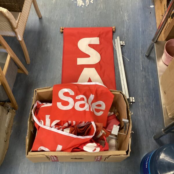 Red sale banners stacked in a box, promotional retail signage.