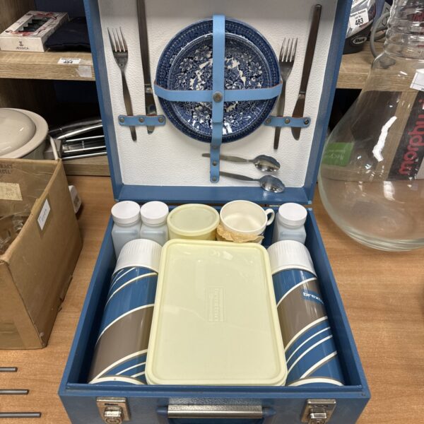 Open vintage Brexton picnic set showing enamel plates and cups.