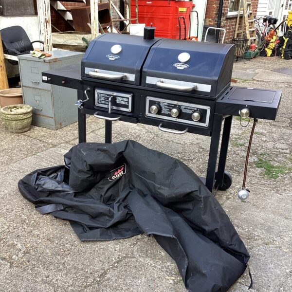 Black Uniflame gas barbecue with protective cover displayed outdoors.