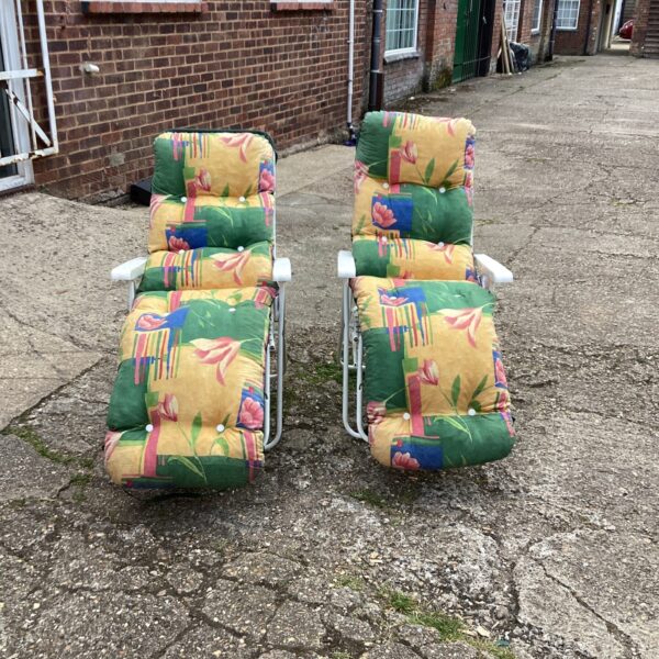 Colourful floral patterned folding garden sun loungers in a garden setting.