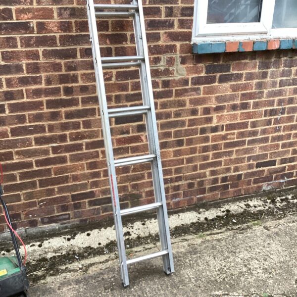 Silver aluminium extending ladder leaning against a brick wall.