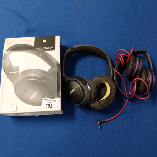 Pair of Bose and Beats over-ear headphones on a blue surface.