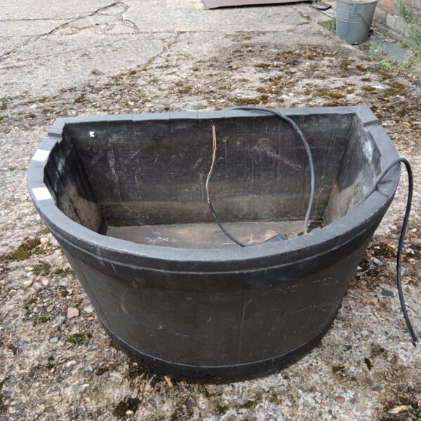 Dark plastic faux barrel for a garden water feature.
