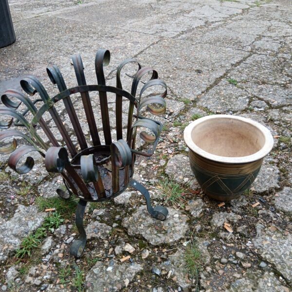Green plant pot in decorative metal basket for garden display.