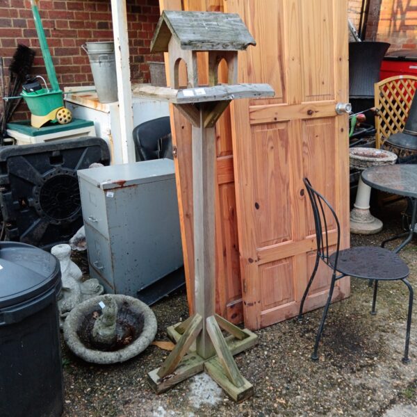 Rustic wooden garden bird table in a garden setting.